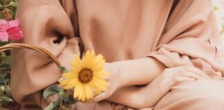 Salon Muslimah Syar’i di Kota Banjar A woman sitting on a bench with a basket of sunflowers