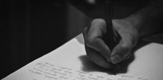 Puisi Tentang Ilmu vs Kebodohan A person writing on a notebook with a pen