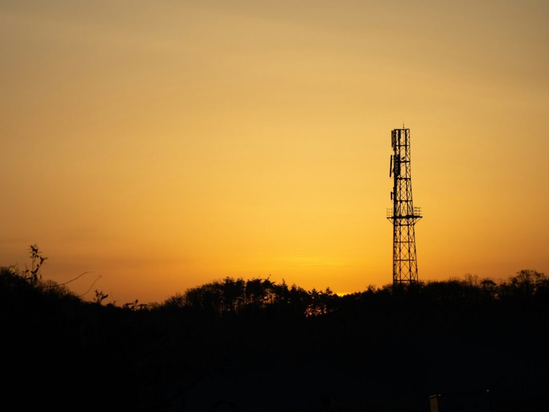 Photo by Hanae Dan a tall tower sitting on top of a lush green hillside