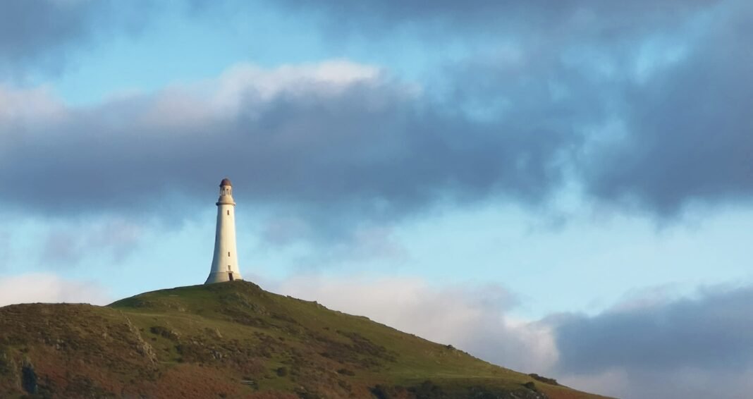 Photo by J Lopes white lighthouse on top of hill