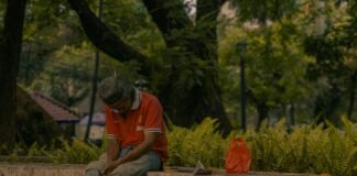 Keluh Kesah Pengangguran 5 Tahun A man sitting on a stone wall in a park