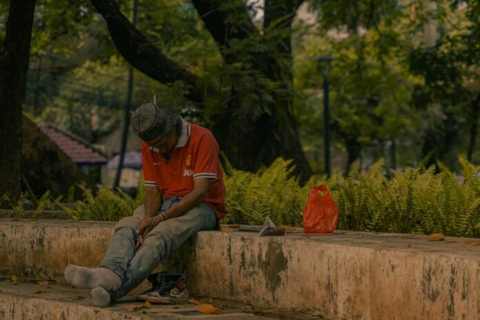 A man sitting on a stone wall in a park