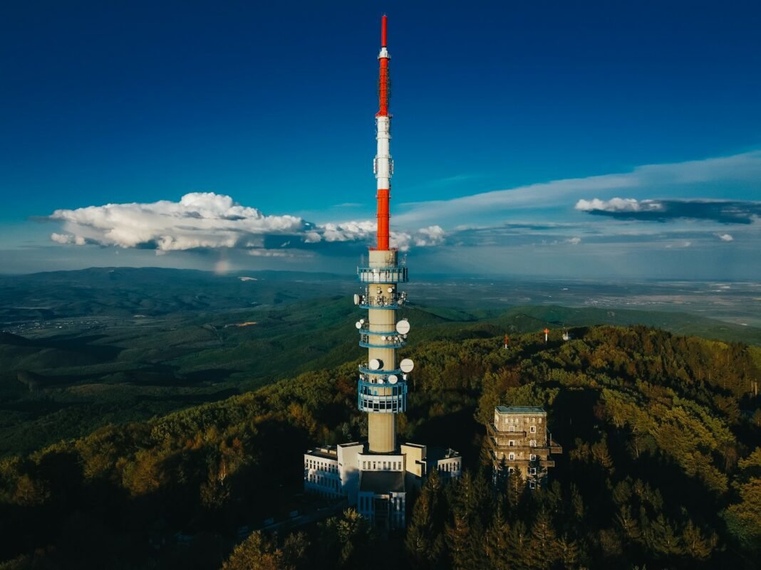 Photo by Ádám Berkecz white and red tower on top of mountain under blue sky during daytime