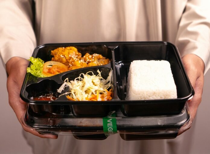 A person holds a bento box meal.